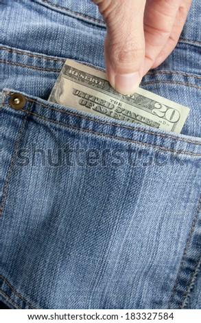 A person pulling a twenty dollar bill out of a denim blue jean back pocket