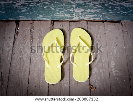 A pair of yellow flip-flops sitting on the porch