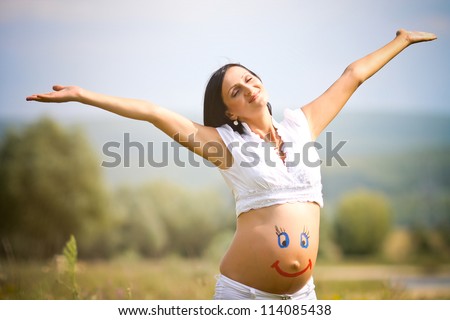 Painted  happy smiley face on the belly of pregnant woman