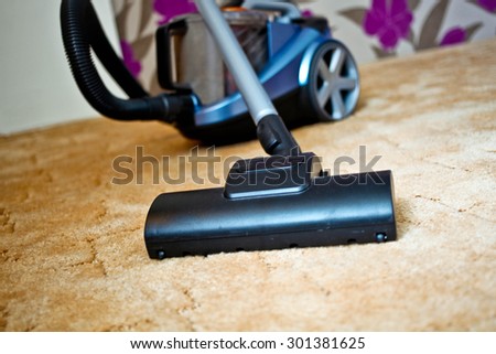 Close up of the head of a modern vacuum cleaner being used while vacuuming a thick pile  carpet
