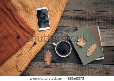 Cup of tea with old book, autumn leaves on wooden table.