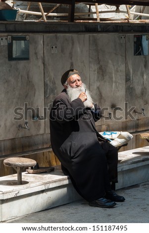IZMIR, TURKEY - APRIL18: An unidentified religious old man with traditional clothes combs his beard before entering the mosque for the prayer on April 18, 2009 in Izmir, Turkey.