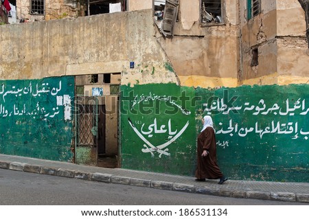 BEIRUT, LEBANON - DECEMBER 29, 2005: An unidentified woman walks by a destroyed house in the former Green Line.