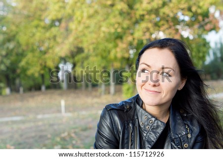 Smiling woman sitting daydreaming and looking at the sky in wooded countryside