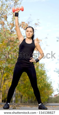 Low angle view of a fit athletic woman exercising with a dumbbell raising her arm above her head