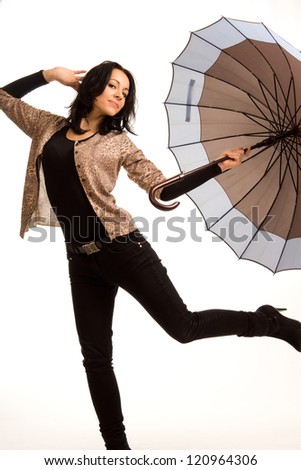 Playful beautiful young brunette woman posing with an umbrella with one leg raised in the air isolated on white