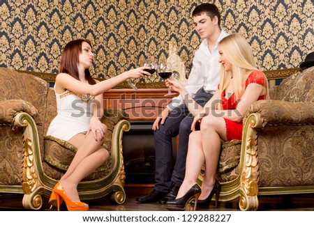 Happy fashionable elegant young friends having a drink together clinking their glasses in a celebratory toast