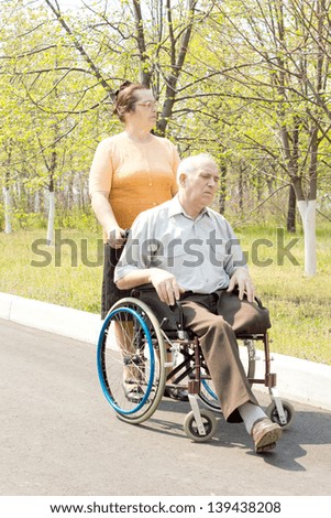 Woman pushing senior man in wheelchair in the park