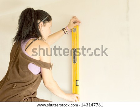 DIY young attractive woman using spirit level to work out measurements.
