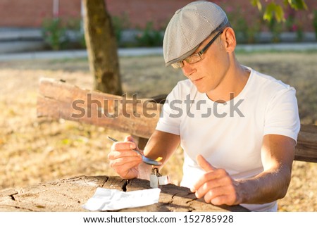Depressed Caucasian middle-aged man preparing a drug dose in order to get high outdoors