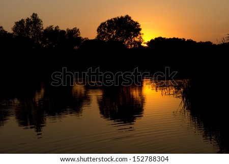 Scenic nature image with sunlight reflected in the surface of a lake at sunset