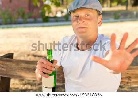 Ashamed adult man addicted to alcohol holding a bottle refusing to be seen and photographed
