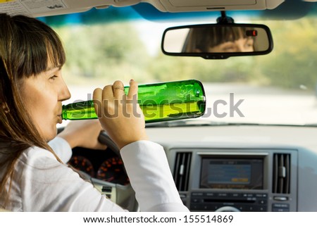Intoxicated woman drinking and driving as she swigs alcohol from the bottle while driving down the road
