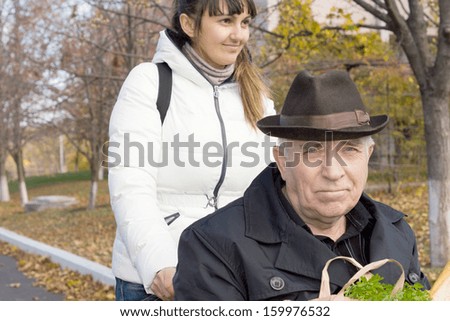 Close up portrait of an elderly man in a wheelchair being taken out grocery shopping by a smiling middle-aged woman
