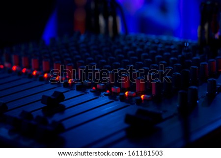 Close up view at night of the volume and mixing sliders on a DJ music deck for mixing and fading the audio on the recorded soundtracks at a disco, concert or party