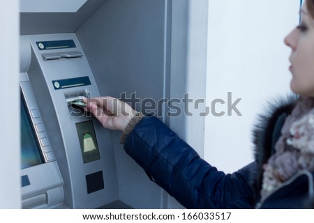 Woman inserting her bank card in an ATM as she prepares to with draw or deposit money