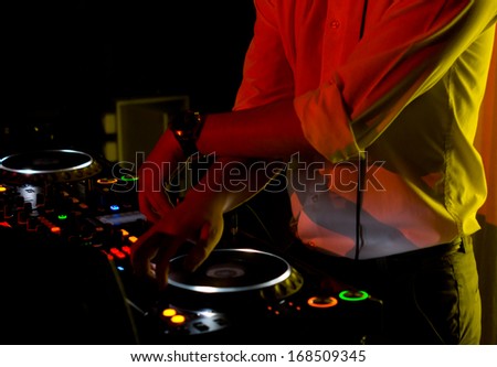 Hands of a young disc jockey scratching and mixing music with vinyl discs on the turntables of his deck