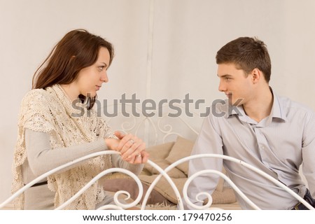 Young couple sitting having a private discussion as they relax on an old wrought iron sofa or bed looking deeply into each others eyes