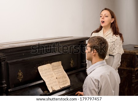 Young couple giving a singing recital with an attractive young female vocalist accompanied on the piano by a young man