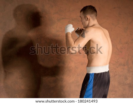 Young boxer in fitness training working out casting a shadow on a dark brown background with copyspace