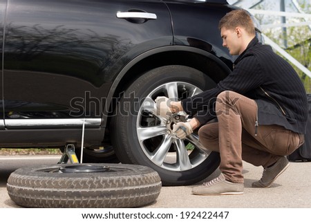 Mechanic changing a wheel during a roadside assistance call out to assist a driver in an emergency following a puncture