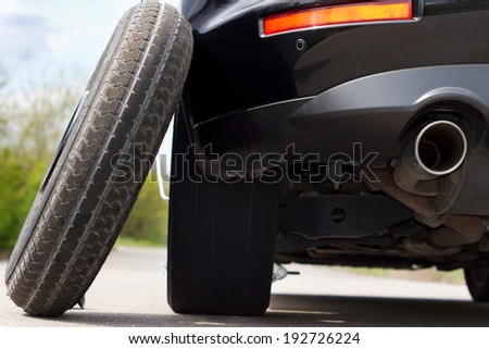 View from the back of the vehicle showing the exhaust pipe of a spare tyre balanced against a car
