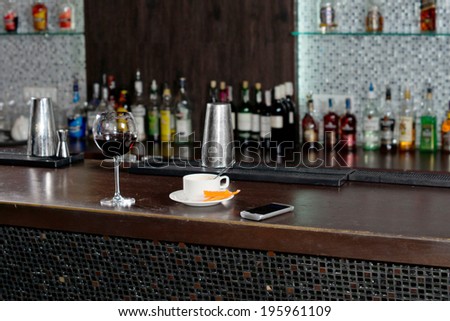Cup of coffee standing on a bar counter alongside a half empty glass of red wine after a customer has tried to sober up before leaving for home