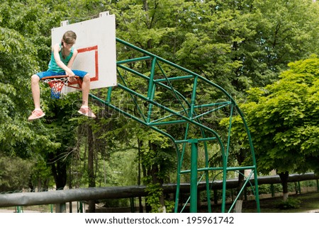 Young girl replacing a basketball net sitting balanced on top of the metal hoop carefully threading the net onto the ring, against greenery with copyspace