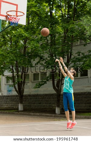 Teenage girl playing basketball shooting the ball at the hoop as she tries to score a goal