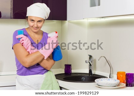 Lady holding spray cleaner and kitchen sponge with a smirk on her face