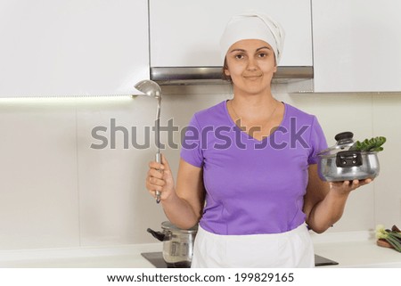 Female Cook in the kitchen smiling while holding pot and ladle