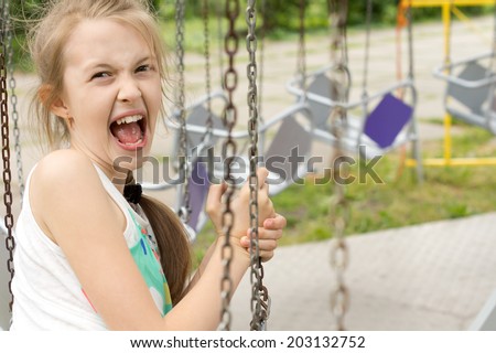 Funny cute girl screaming in the chair swing ride while experiencing mixed feelings and emotions,as excitement, joy and fear, in the amusement park, in summer