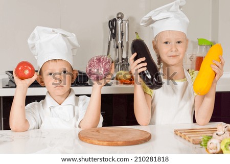 Two Chefs Holding Big Vegetables in the Kitchen. Looking at Camera.