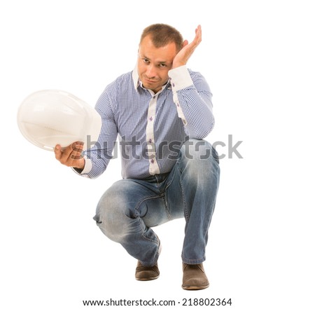 Crouching Man with Hard Hat Resting Head on Hand and Looking Troubled in Studio with White Background