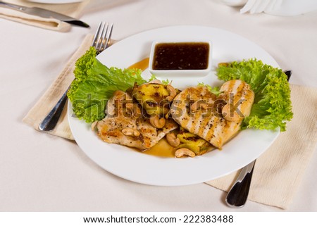 Gourmet Well-Cooked Meaty Main Dish with Spicy Dipping Sauce on White Round Plate, Served on White Dining Table with Utensils on Sides.
