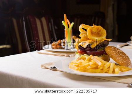 Gourmet Cheeseburger and French Fries on Table in Restaurant