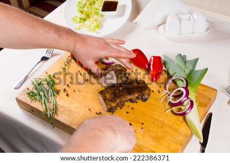 Slicing Appetizing Cooked Meat on White Table Using Wooden Chopping Board with Spices on Sides.