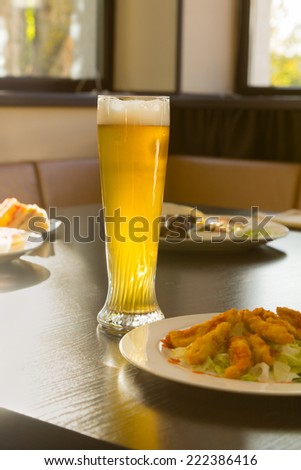 Tall Glass of Beer on Restaurant Table with Plated Food Dishes