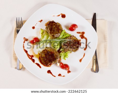 Gourmet Tasty Meaty Main Dish with Herbs and Vegetable on Semi Square White Plate, Served on White Table.