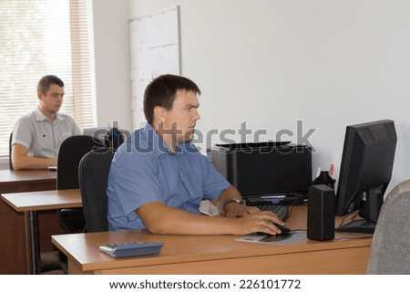 Middle Age Male Office Workers at their Designated Table Area Busy Working with Computer.