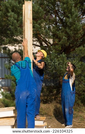 Group of construction workers aligning a prefab wooden wall panel on a new build house
