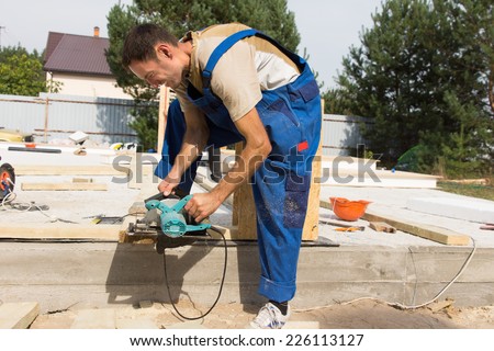 Carpenter sanding a wooden beam on a building site for a new house construction