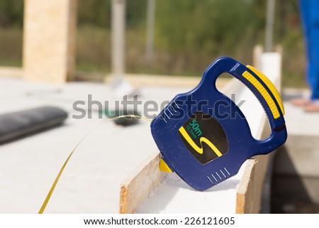 Builders blue plastic retractable tape measure resting on an insulated wall panel on a building site