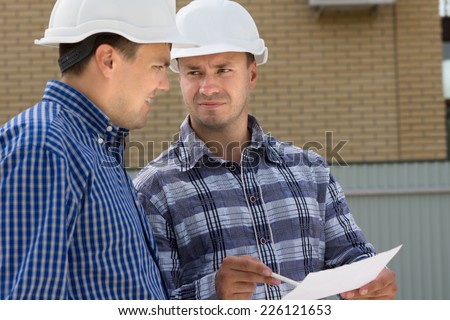 Middle Age Male Engineer and Foreman Discussing the House Project at the Construction Site.