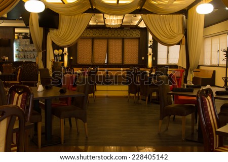 Interior decor of an empty nightclub with a small stage for live performances and tables and chairs for patrons