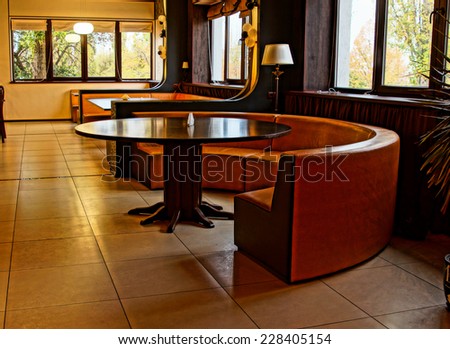 Curved modern bench around a table in an upmarket nightclub, restaurant or bar with windows along the walls