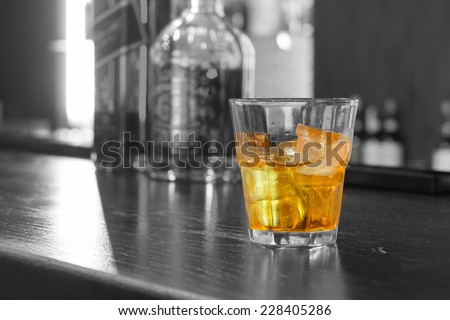 Glass of iced whiskey on the rocks in a glass tumbler standing on a bar counter , close up with copyspace