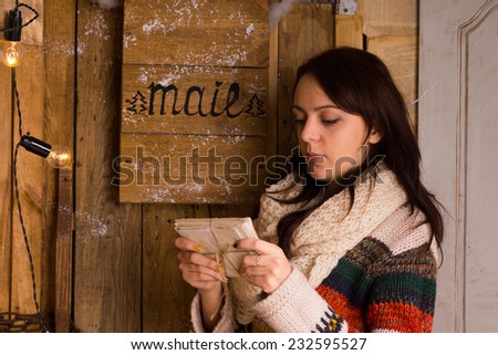 Woman examining a bundle of letters tied with string from the mail box with a serious contemplative expression, side view
