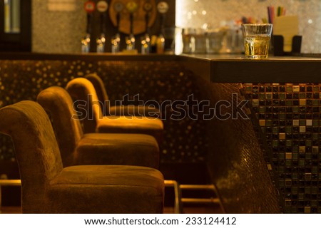 Comfortable vacant seating in a nightclub in front of the bar counter in glowing ambient light