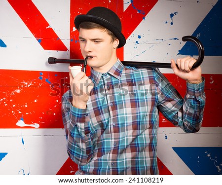Close up Smoking Young Man in Casual Outfit with Cane on his Shoulder in front Huge UK Flag Print.